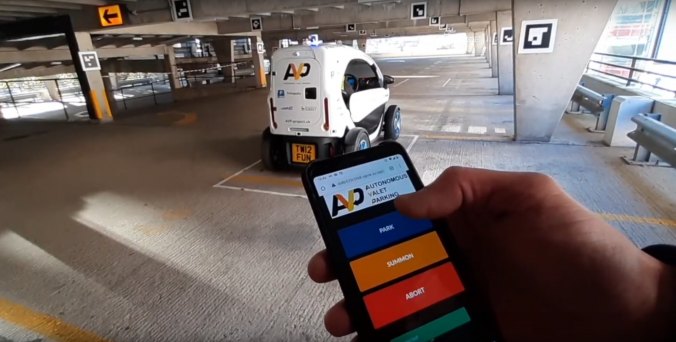 Parkopedia's SD Twizy pictured with a phone displaying a summoning app in the foreground